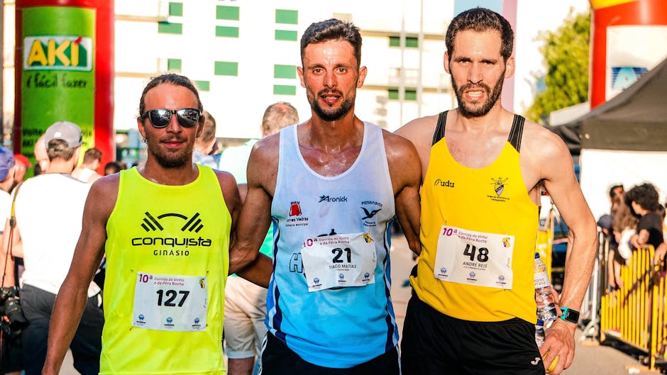 Three marathon runners posing with race bibs after completion